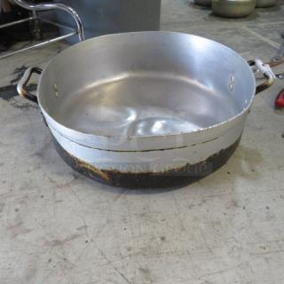 Aluminum braizing pan, 19x6 inches, shows wear with blackened bottom. Riveted handles, suitable for heavy-duty cooking.