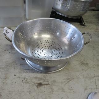 15-inch aluminum colander with dual handles, perforated for draining. Slight wear visible; ideal for kitchen use.