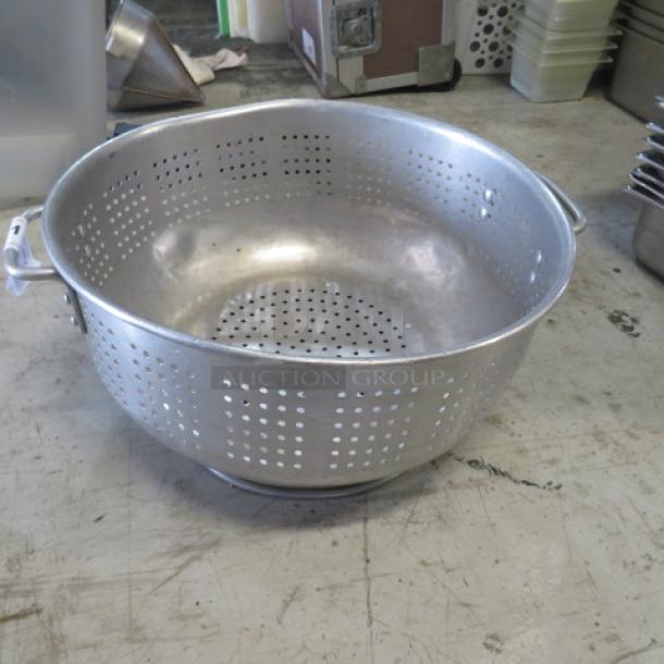 16-inch aluminum colander with perforated design and two side handles. Good condition, ideal for straining and rinsing.