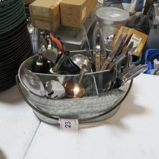 Aluminum holder with assorted flatware, including spoons and knives, in used condition. Auction tag number 23 visible.