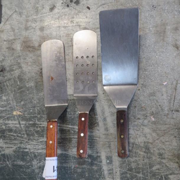 Assorted hamburger turners with wooden handles; includes solid, slotted, and perforated designs. Used condition.