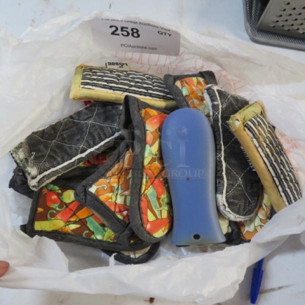 Lot of colorful, quilted handle mitts in mixed patterns and a blue handle grip, stored in a plastic bag. Auction tag reads "258."