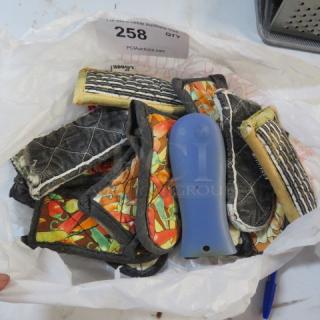 Lot of colorful, quilted handle mitts in mixed patterns and a blue handle grip, stored in a plastic bag. Auction tag reads "258."