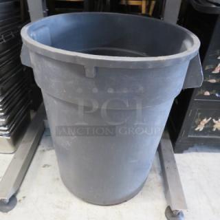 Rubbermaid Brute trash can, grey, used condition, cylindrical design, durable plastic, visible scuffs, no lid.