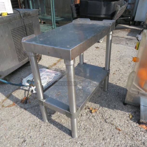 Stainless steel table with under shelf, 12x24x24 inches. Features sturdy legs, durable construction, lightly scuffed finish.
