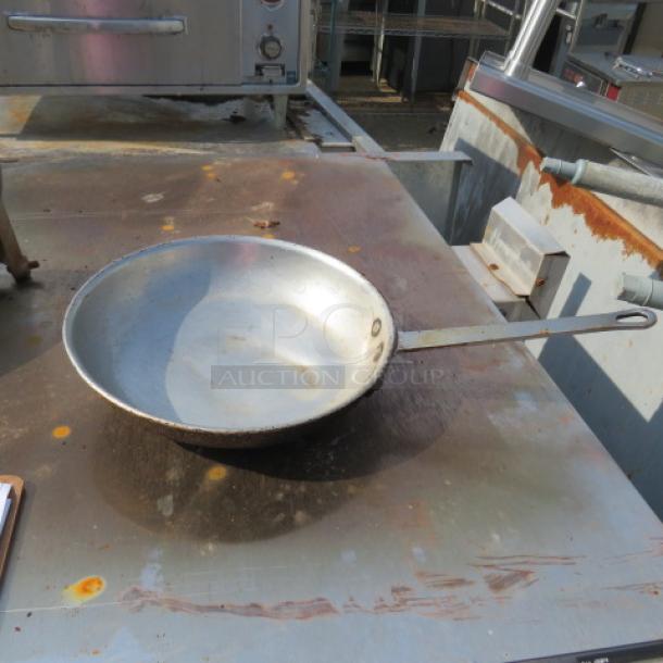 10-inch skillet, moderately used, showing wear and rust on cooking surface and handle; industrial setting background.