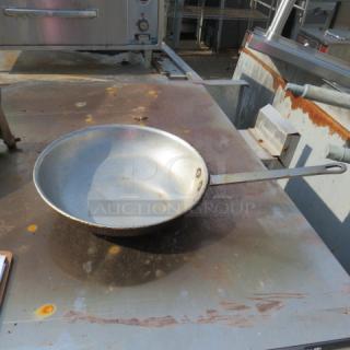 10-inch skillet, moderately used, showing wear and rust on cooking surface and handle; industrial setting background.