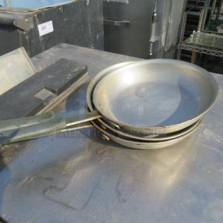Three stacked 10-inch skillets with signs of wear on a metal surface. Handles visible, showing used condition.