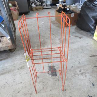 Orange metal magazine rack holder, dimensions 13x10x32 inches. Features wireframe design and visible signage hook. Good condition.