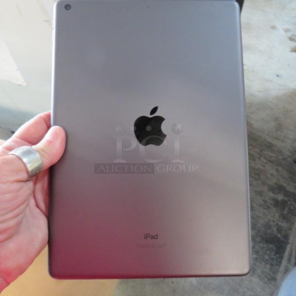 Apple iPad A2602 in space gray, good condition, back view showing Apple logo and "iPad" marking, held in hand.