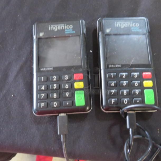 Ingenico CC Mobile MOBY8500 card readers, pair, used condition, black, featuring numeric keypad, visible charging cables.