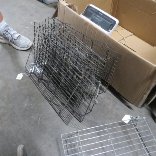 One lot of 19 metal cooling racks in used condition, stacked near an open cardboard box.