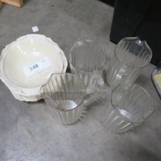 Set of four clear glass pitchers with ribbed design, alongside a white ceramic bowl. Condition appears used. Numbered tag 348 visible on the bowl.