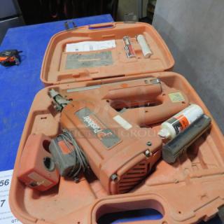Paslode cordless 30-degree framing nailer in orange case. Includes fuel cells and charger. Used condition with visible dust.