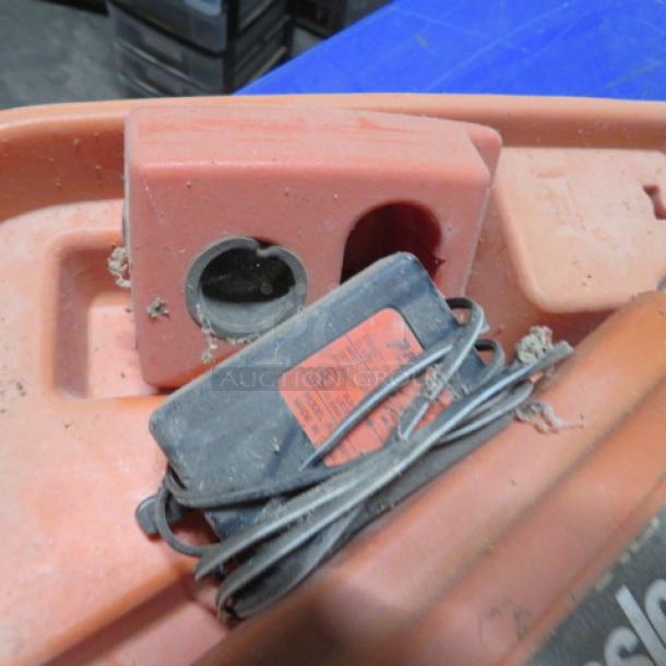 Paslode Cordless 30 Degree Framing Nailer in orange case, shown with charger. Signs of wear and dust visible.