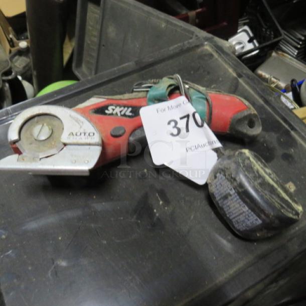 Skil Saw #889, handheld, red and black, visible wear. Includes a tag marked "370." Cordless with a detachable battery.