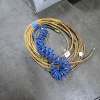 Assorted air hoses, including coiled blue and straight yellow hoses, with metal connectors; suitable for industrial use.
