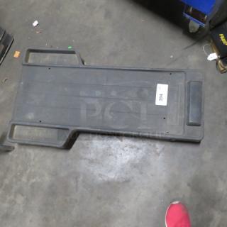 Black mechanic creeper in used condition, with side handles and padded headrest. Tag shows number "394." Suitable for car repairs.