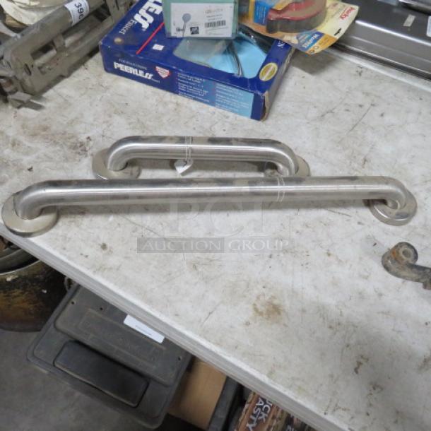 Assorted size grab bars, 13-inch and 24-inch, stainless steel, used condition, laid on a workbench.