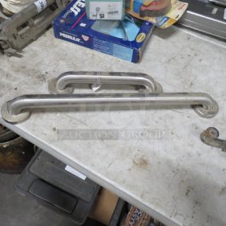 Assorted size grab bars, 13-inch and 24-inch, stainless steel, used condition, laid on a workbench.