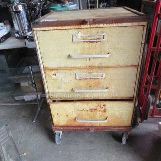 Metal cabinet on casters, four drawers, dimensions 27.5x25x43 inches, distressed condition, visible rust.