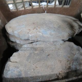 A stack of natural stone pavers, irregular shape, in used condition with visible dirt and wear, ideal for garden landscaping.
