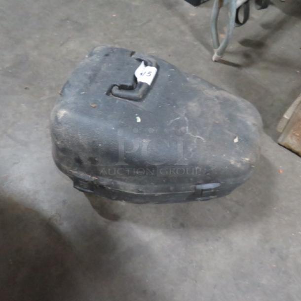 Black plastic chain saw case, scuffed and used condition, with a latch and visible handle on top. White paper tag labeled "45".