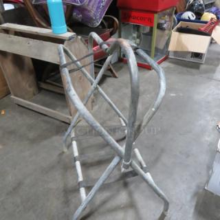 Metal saddle stand in used condition, sturdy construction, light rust, suitable for equestrian saddles.