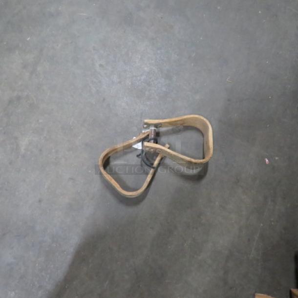 Set of wooden stirrups on concrete floor, showing wear. No visible tags or markings. Stirrups are loop-shaped.