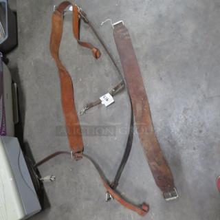 Lot of leather straps, varying widths and lengths, worn condition. Includes buckles, clasps, and a visible tag labeled "54."