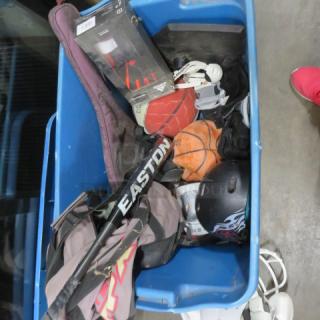 A blue bin filled with assorted sports gear, including an Easton baseball bat, basketballs, helmet, and a sports bag.