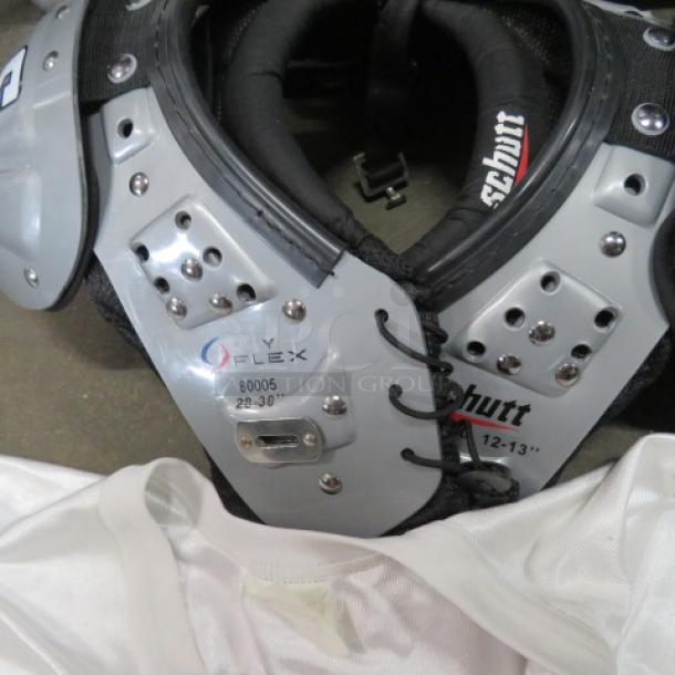 Lot of football gear featuring Schutt shoulder pads, white jersey, and helmet. Pads include Fly Flex and size details.