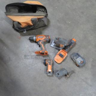 Rigid tool bag with assorted tools including a power drill, reciprocating saw, and battery pack, in used condition.