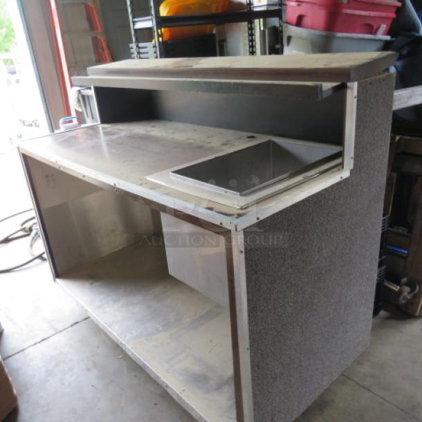 Portable bar with cold well and under shelf on casters. Dimensions: 61x28x50 inches. Well size: 12x19x10.5 inches.
