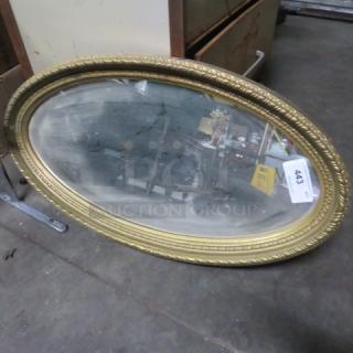 Oval gold-framed mirror with intricate detailing, moderate wear. Auction tag "443" attached.