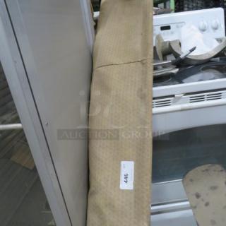 Beige sunshade with a fabric texture, leaning against a metal surface. Item tag reads "446." Appears in used condition.