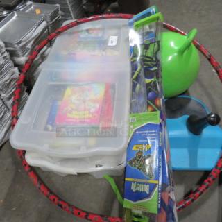 Assorted lot including large hula hoop, green bouncy ball, plastic storage boxes with games, blue toy base, and packaged toy set.