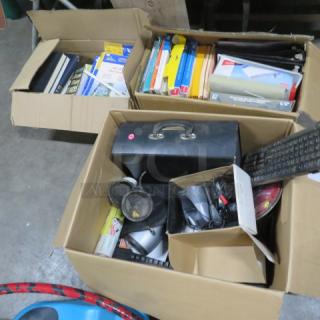 Three boxes filled with miscellaneous items, including books, stationery, electronics, and cables. One box has a black briefcase. Items appear used.