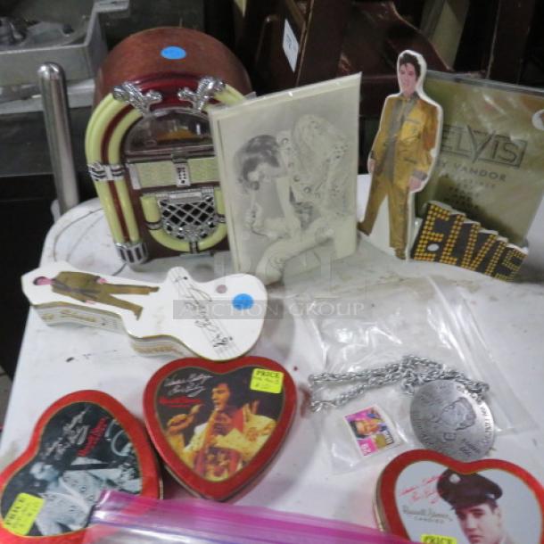 One lot of Elvis/Marilyn Monroe collectibles featuring themed tins, a small jukebox model, photo cards, and a chain with medallion.