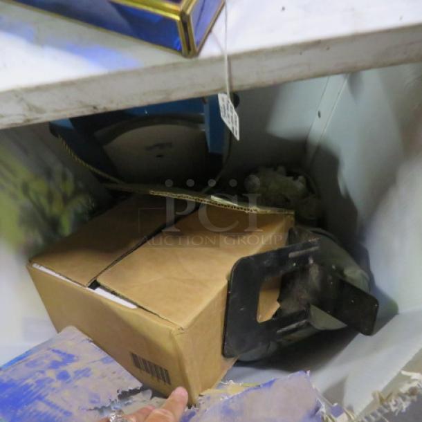 A lot of miscellaneous items including a cardboard box, metal bracket, and assorted packaging on a shelf. Condition varies.
