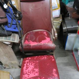 Vintage leather chair with ottoman, red leather with visible wear and peeling, wooden frame.