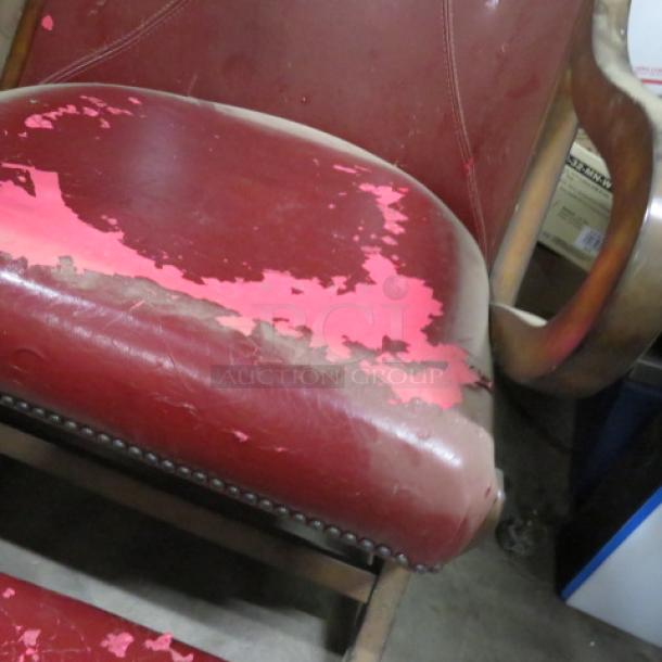 Vintage leather chair with ottoman, distressed red leather with visible wear and peeling, wooden arms and legs.