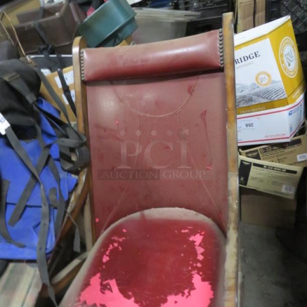 Vintage leather chair with ottoman, distressed red leather, wood frame, visible wear, ornate nailhead trim.