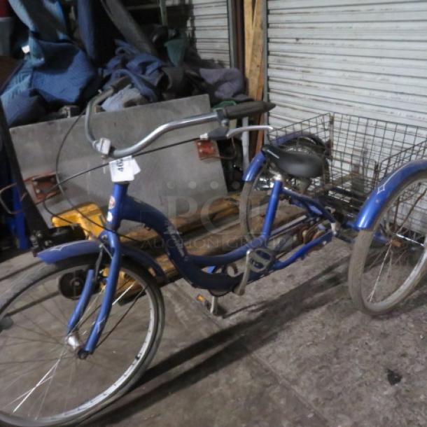 Vintage Schwinn Meridian tricycle with rear basket, blue frame, three wheels, and a comfortable seat. Condition appears used.