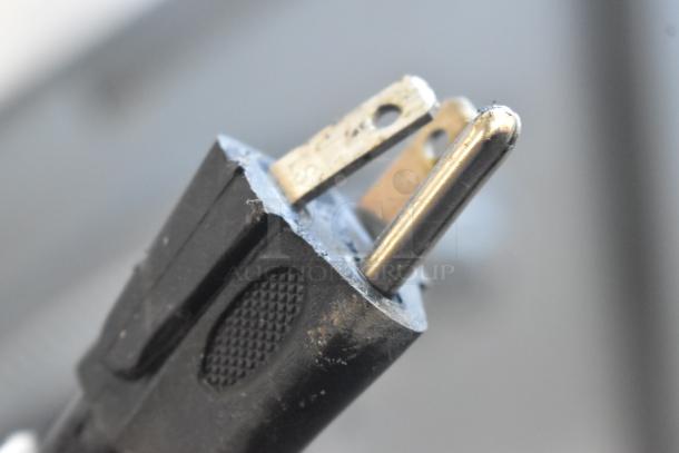 Alt Text: Close-up of a worn black electrical plug with visible metal prongs.