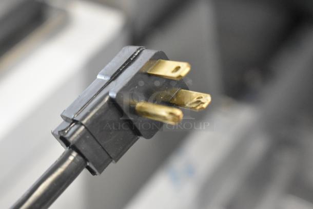 Close-up of a power plug for a Beverage Air SPE27HC-12M stainless steel prep table, showing three prongs.