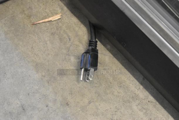 Plug and cable of a Vollrath Cayenne FMA7048 Commercial Heated Display Case resting on a concrete surface.