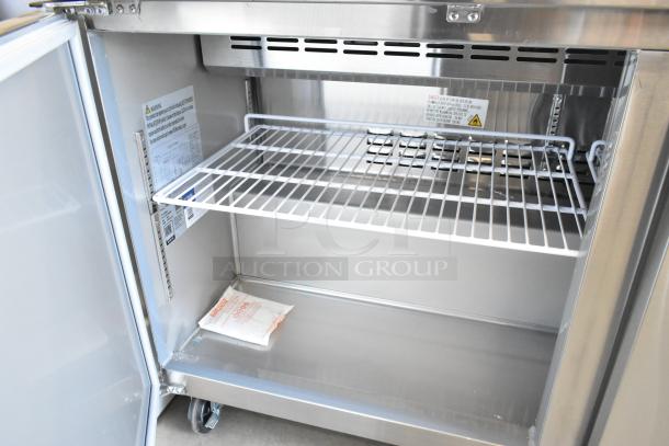 Brand new Avantco 178SSPT6010 2-door stainless steel refrigerated prep table. Interior view with shelf and caster wheels. 115V, 1 phase.
