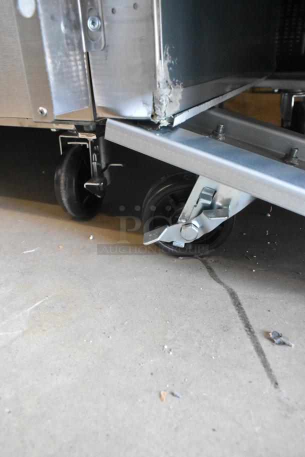 Stainless steel commercial cooler with visible dent, model 829BMR49R, on casters. 115V, 1 phase. Poly coated racks.