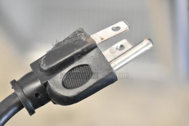 Close-up of a power plug from a 2021 IDW G4-H0234B commercial cooler. Black plastic with silver prongs.
